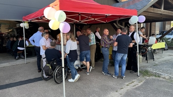 Gäste im Gespräch unter einem roten Pavillon vor der Werkhalle beim Jubiläumsfest