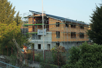 Wohnhaus in Hockenheim mit neuem Dachgeschoss in Holzrahmenbauweise, eingerüstet mit Bauschild von Holzbau Bruder